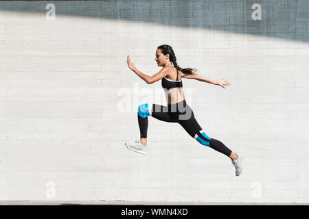 Corps complet de l'athlète féminin dans les vêtements de sport sauter sur le béton Banque D'Images