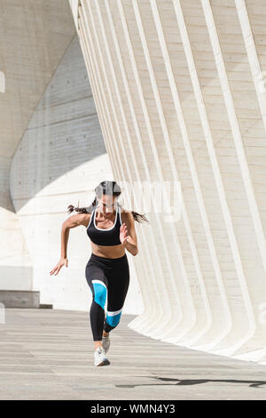 Corps complet de l'athlète féminin dans les vêtements de sport d'exécution sur le béton Banque D'Images