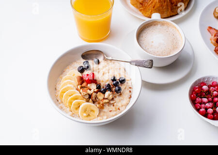 Le petit-déjeuner avec du gruau avec de petits fruits et noix, café et jus d'orange Banque D'Images