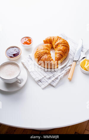 Vue d'en haut flatlay avec croissants frais servis avec des confitures, beurre et café. Concept de repas du matin. Fond blanc Banque D'Images