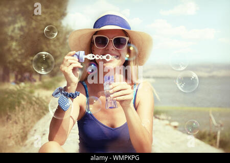 Jeune femme soufflant des bulles de savon dans un parc Banque D'Images
