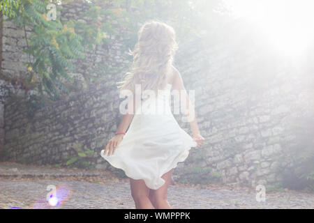 Young woman wearing white dress dancing au parc sur sunny day Banque D'Images