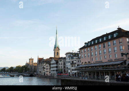 La flèche de l'église Fraumünster au coucher du soleil, avec des magasins et la Storchen Hotel sur la Limmat et pont Münsterbrücke, à Zurich, Suisse. Banque D'Images