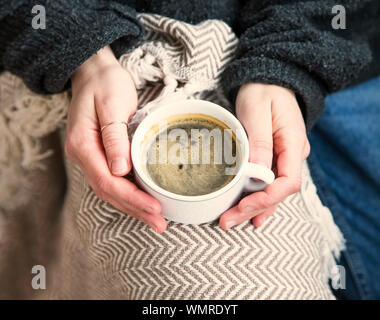 Femme confortable intérieur hands holding tasse de café ou chocolat avec pull et couverture, maison confortable l'hiver ou l'automne chaud avec concept de vie dr Banque D'Images