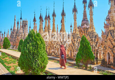 Le moine bhikkhu en habit rouge promenades le long de la rangée de stupas funéraires ancinet, préservés dans les pagodes Myanmar Kakku site, Banque D'Images