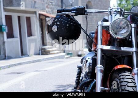 Moto rouge avec un casque suspendu au guidon tiré de l'avant Banque D'Images