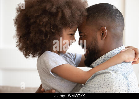 Close up head shot happy little daughter hugging papa. Banque D'Images