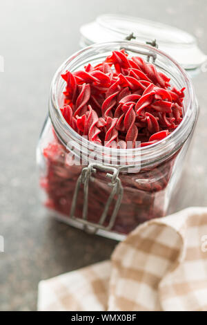 Pâtes colorées non cuites avec saveur de betterave dans le bocal. Banque D'Images