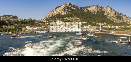 Île de Capri, ITALIE - AOÛT 2019 : vue panoramique sur le port de l'île de Capri. Un ferrry est amarré dans le port et les petits bateaux s'en vont. Banque D'Images