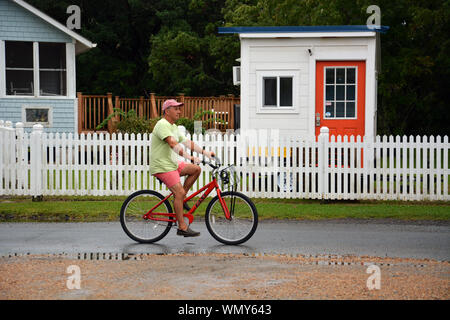 Un homme conduit une bicyclette dans les rues de la plage de la communauté d'Ocracoke dans les Outer Banks de Caroline du Nord. Banque D'Images