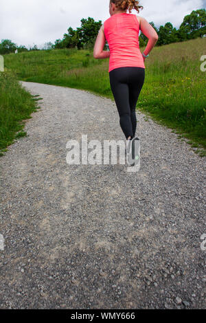 Fit woman court le long chemin de terre en guêtres noires et rose top Banque D'Images