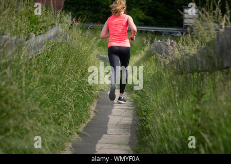 Fit woman court le long chemin en guêtres noires et rose top Banque D'Images