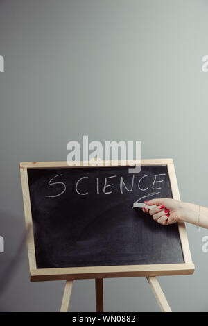 Un professeur de science d'écriture, le dessin des éléments de chimie sur tableau noir à la main, fond gris Banque D'Images