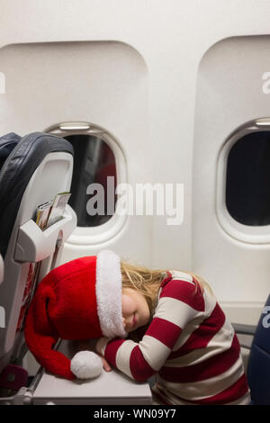 Girl wearing Santa hat sleeping on airplane Banque D'Images