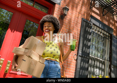Femme transportant des boîtes de carton et jus vert Banque D'Images