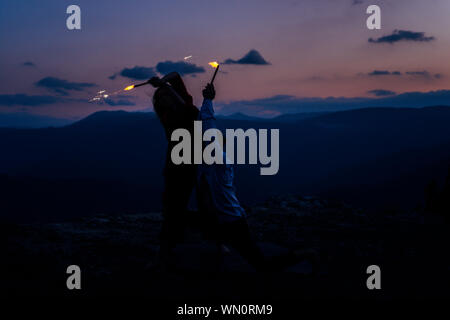 Les jeunes jouant avec cierges dans la nuit. Best Friends hanging out at night sur la falaise de montagne Banque D'Images