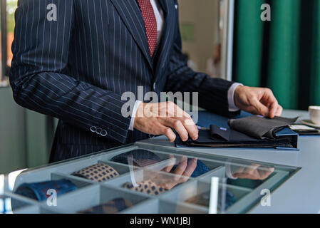 Shop assistants, qui pinstripe suit holding swatches Banque D'Images