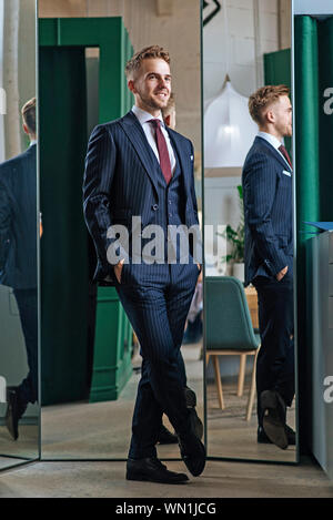 Smiling man wearing pinstripe suit par des miroirs Banque D'Images