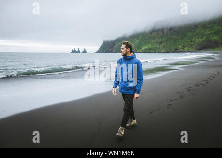 Homme marchant sur la plage de Vik, Islande Banque D'Images