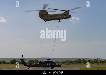 Un CH-47 Chinook à partir du 1er bataillon du 228e Régiment d'aviation met un UH-60 sur la piste sur l'aéroport de Liberia, Costa Rica, le 29 juillet 2019. Lors d'une mission à l'appui de l'USNS Comfort, l'UH-60 équipage a effectué un atterrissage de précaution dans un environnement austère au Costa Rica. Après avoir inspecté le Blackhawk, l'équipage a déterminé que l'aéronef n'a pas voler en toute sécurité. Service commun des membres de la Force opérationnelle - Bravo ont travaillé ensemble, avec l'aide d'un C-17 Globemaster III à partir de la commande de transport américain, pour retourner l'hélicoptère cassé retour à Soto Cano. (U.S. Photo de l'Armée de l'air par Te Banque D'Images