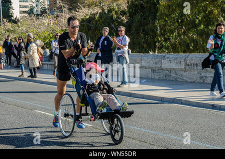 Homme qui va pousser son fils dans la voiture de marathon de Valence en Espagne le 16 novembre 2014 Banque D'Images