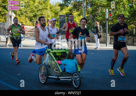 Homme qui va pousser son fils dans la voiture de marathon de Valence en Espagne le 16 novembre 2014 Banque D'Images