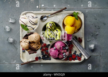 Un assortiment de saveurs et les couleurs de la crème glacée italienne gastronomique servi sur table en acier. Mangue, chocolat, glace matcha vert Banque D'Images