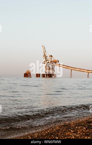 Plan vertical d'une grue métallique dans l'eau avec un ciel clair en arrière-plan Banque D'Images