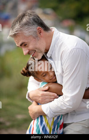 Transmission de père aimant hugging son mignon fille à la peau sombre Banque D'Images