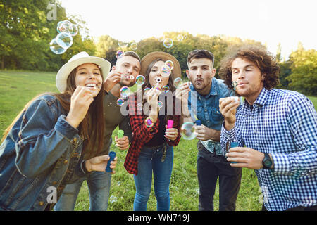 Jeunes amis soufflant des bulles de savon dans park