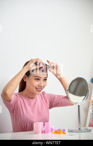 Belle femme avec des bigoudis smiling en miroir, profitant de son regard, la beauté Banque D'Images