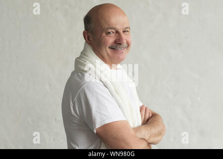 Soins du corps le matin. Hisanic Senior homme après le rasage debout avec serviette blanche et souriant. Banque D'Images