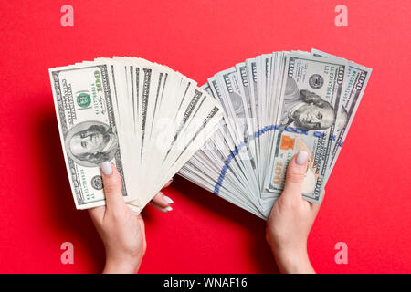 Fan de new one hundred dollar bills en main de femme et une vieille d'une centaine de dollars dans une autre main sur fond coloré. Concept d'investissement. Banque D'Images