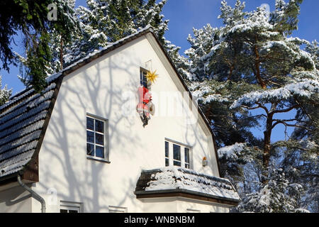 Housebreaker déguisé en Père Noël monte jusqu'à briser le mur de la maison dans une maison par une fenêtre Banque D'Images