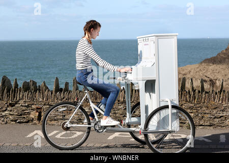 Busker Ilfracombe Chloe Aston représenté sur son vélo piano unique qu'elle utilise pour divertir les foules quand elle effectue Banque D'Images