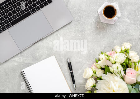 Mise à plat, vue du dessus table office 24. Espace de travail avec ordinateur portable, agenda, fleurs, tasse de café sur fond noir en béton. Espace Féminin conc Banque D'Images