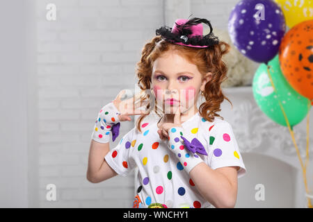 Fille aux cheveux roux à l'image d'un clown . Dans une chambre blanche avec des ballons. Banque D'Images