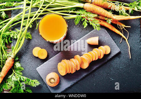 Vue de dessus au jus de carotte bio végétarienne fraîche sur une table de cuisine en bois Banque D'Images