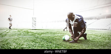 African American male rugby player attacher ses lacets dans le stade Banque D'Images