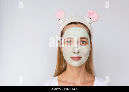 Portrait of a young woman applying avocat naturel masque sur son visage sur fond blanc. Soins de la peau et des soins spa à domicile ou salon de beauté Banque D'Images