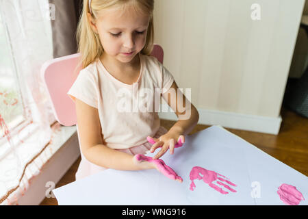 Portrait of a cute little girl painting mains à la maison. Apprendre, l'éducation, l'enfance heureuse concept Banque D'Images