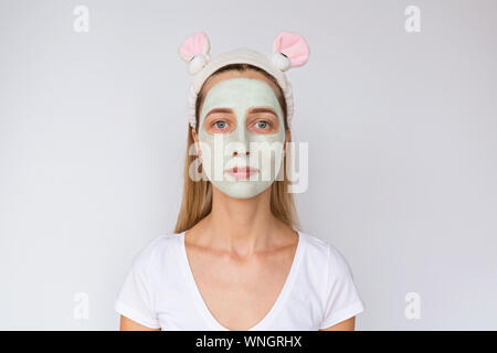 Portrait of a young woman applying avocat naturel masque sur son visage sur fond blanc. Soins de la peau et des soins spa à domicile ou salon de beauté Banque D'Images