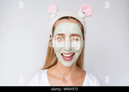 Portrait of a young woman applying avocat naturel masque sur son visage sur fond blanc. Soins de la peau et des soins spa à domicile ou salon de beauté Banque D'Images