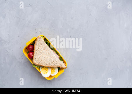 Fournitures scolaires et boîte à lunch avec sandwich et de légumes. Retour à l'école. De saines habitudes alimentaires concept - mise en page avec l'arrière-plan de l'espace texte libre Banque D'Images