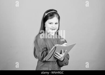 Vous permet de regarder dans le livre de la connaissance scientifique. Adorable petit enfant écrit connaissance rapport d'essai. Adorable petite fille tenant en mains. connaissances livre Jour des connaissances ou le 1 septembre. Banque D'Images