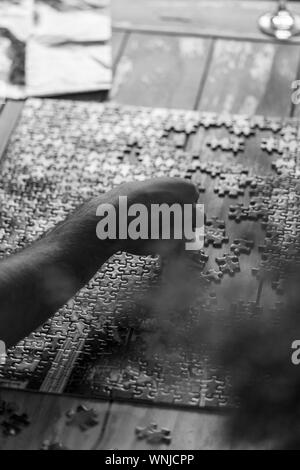 Image en noir et blanc. L'homme est fait sur le puzzle table basse en bois. Image en noir et blanc Banque D'Images