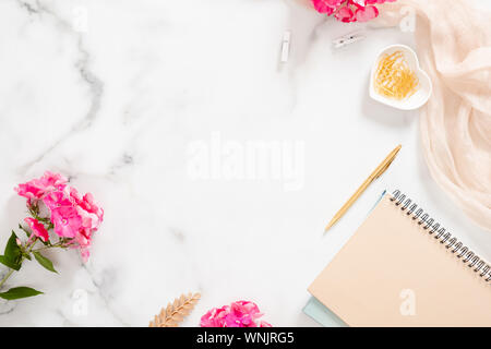 Flatlay accueil bureau bureau table. Espace de travail avec ordinateur portable beige pastel, rose Fleurs et décorations sur fond blanc. Mise à plat, vue du dessus. Banque D'Images