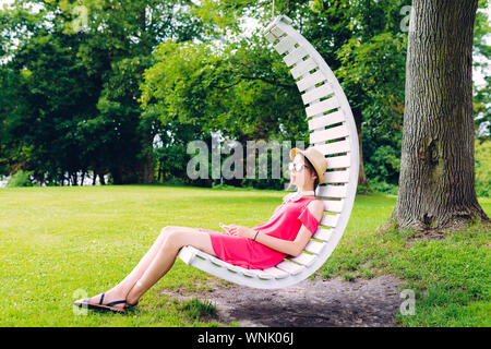 Jeune fille se reposant sur une chaise en bois dans le jardin Banque D'Images