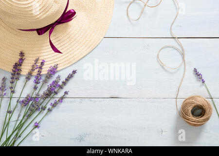 Cadre rond de chapeau de paille, des fleurs de lavande, de la ficelle sur fond de bois bleu rustique. Mise à plat, vue du dessus, copiez l'espace. @Summer mode concept. Banque D'Images