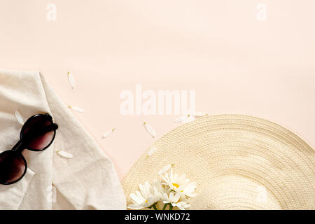 Flatlay la composition avec des accessoires de mode, chapeau de paille, lunettes, daisy fleurs sur fond rose pastel. Mise à plat, vue du dessus, les frais généraux. Le SAF Banque D'Images